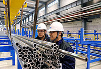 Two persons in a tube factory.